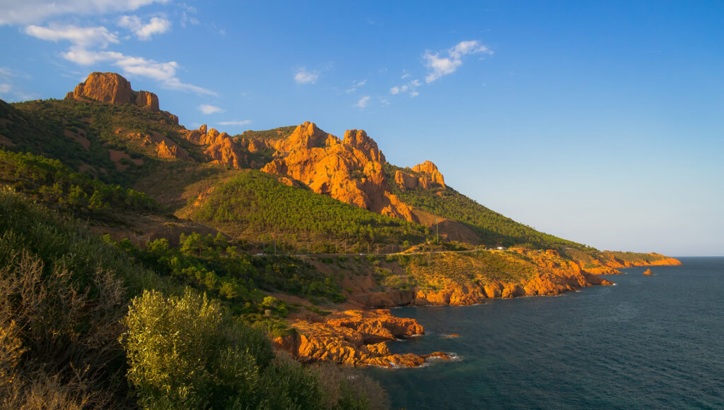 Red porphyry cliffs of the Estérel massif meeting the Mediterranean Sea at golden hour