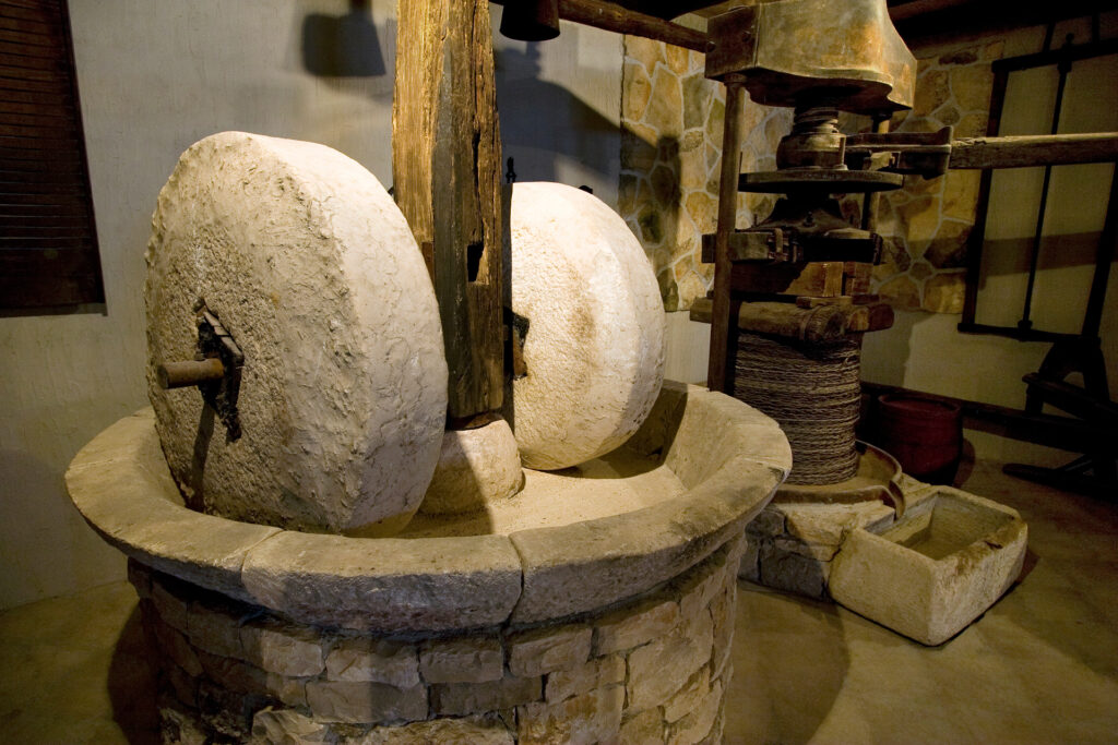 Traditional Provençal olive oil mill with large stone grinding wheels and a wooden press