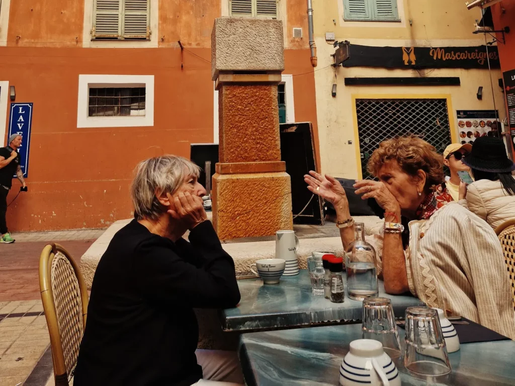 Two women in conversation at a café terrace in Nice